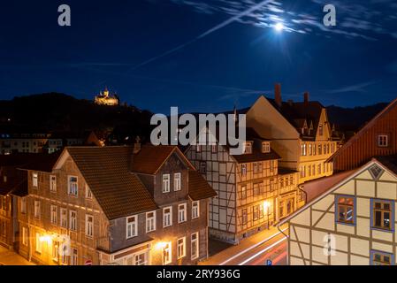 Historic half-timbered houses, behind them Wernigerode Castle in the moonlight, Wernigerode, Saxony-Anhalt, Germany Stock Photo