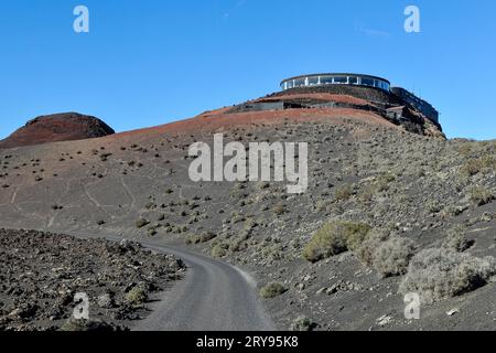 View of volcanic hilltop with tourist centre in Timanfaya National Park with panoramic restaurant El Diablo designed by Cesar Manrique, in the Stock Photo