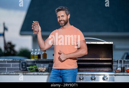 man cooking at a backyard barbecue. expertly grilled barbecue. man tending to the grill cooking delicious barbecue under the open sky. eye fillet Stock Photo