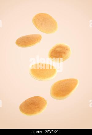 Tasty fresh pancakes falling on beige background Stock Photo