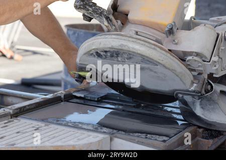 Working on wet saw machine using diamond blade to cut ceramic tile Stock Photo