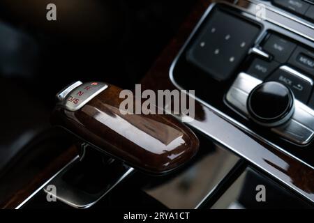 Interior of modern luxury car. Details of automatic transmission gear shift, multimedia control system, car control panel, Air Vent Red emergency button and dashboard inside. Prestige sport automobile. Selective focus Stock Photo