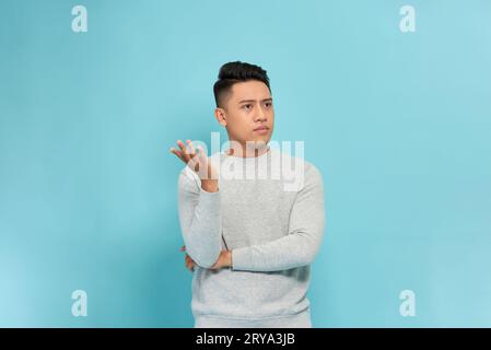 Young asian man explains to someone isolated on blue background Stock Photo