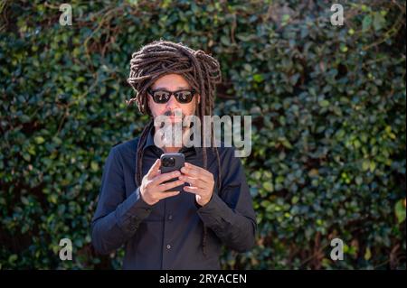 Man with locs hairstyle using his phone Stock Photo