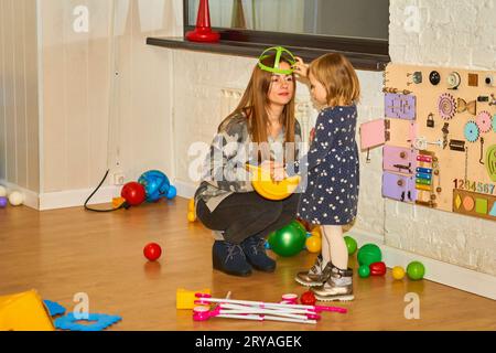 Pretty mother playing with daughter girl,playroom  Stock Photo