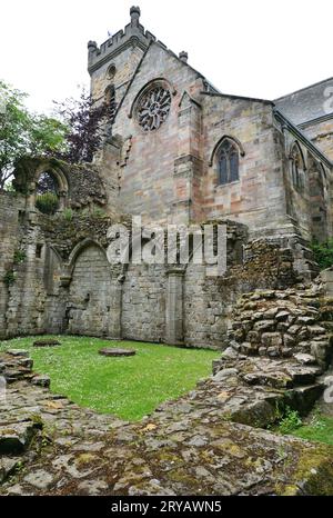 Culross Abbey rises above the ruins of its 13th century cloisters in the foreground. The remaining intact part serves as the local parish church. Stock Photo