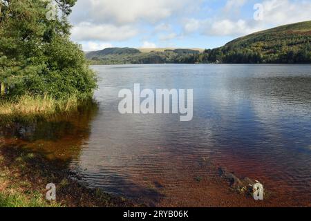 Pontsticill Reservoir in the Central Brecon Beacons below Pentwyn Reservoir, with both cloud reflections in the water and trees surrounding the edges Stock Photo