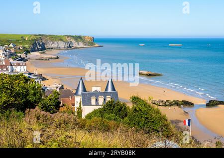 View over Arromanches beach in Normandy on a sunny day with remains of the WWII Mulberry harbour lying on the sand and the Phoenix caissons in the sea Stock Photo