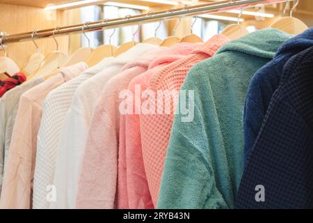 bathrobes of different colors hang on a hanger in the store Stock Photo