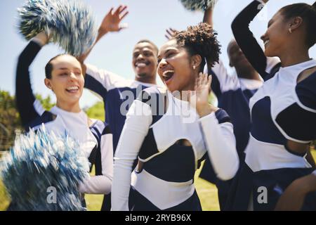 Cheerleaders, outdoor and team for celebration, smile and winner with happiness, excited and teamwork. Women, men and group cheering, grass field or Stock Photo