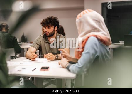 Young, multicultural, entrepreneurs discussing new strategy to increase productivity at work during meeting at table in the office. Stock Photo