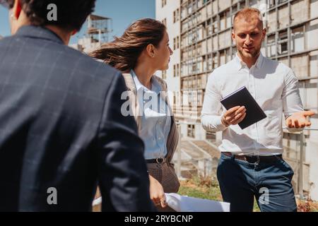 Excited male architect explaining interesting project to his teammates during meeting out in the city, on a sunny day Stock Photo