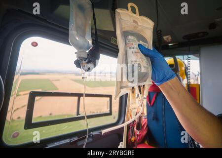 Hand of doctor holding transfusion bag with blood on board helicopter of emergency medical service during flight to hospital. Themes rescue, urgency a Stock Photo