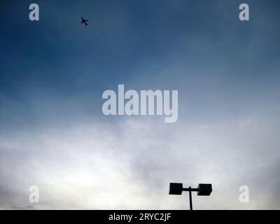 Airplane flying hight over the light pole Stock Photo