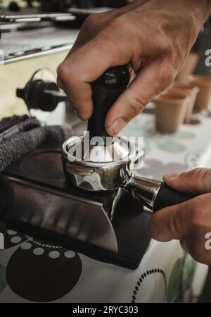 Barista preparing coffee in coffee machine with equipment - vertical photo. Closeup of coffee making process. Hands of barista using a coffee machine. Stock Photo