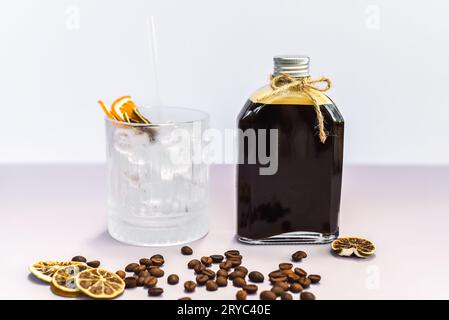 Cold brew coffee in a bottle with transparent glass full of ice on light gray background Stock Photo