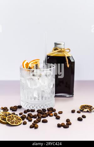 Cold brew coffee in a bottle with transparent glass full of ice on light gray background Stock Photo