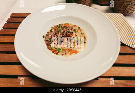 Fresh lentil soup in a white bowl, served in a restaurant setting