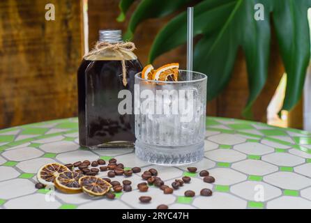 Cold brew coffee in a bottle with transparent glass full of ice on light gray background Stock Photo