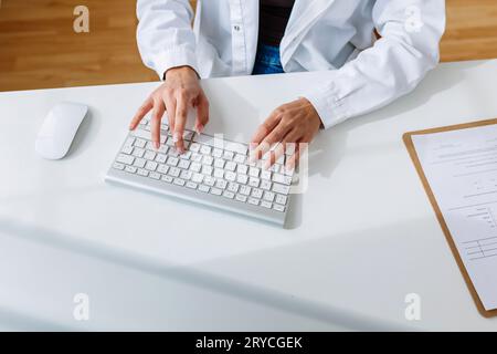 Unrecognizable female doctor working on laptop at clinic office Stock Photo