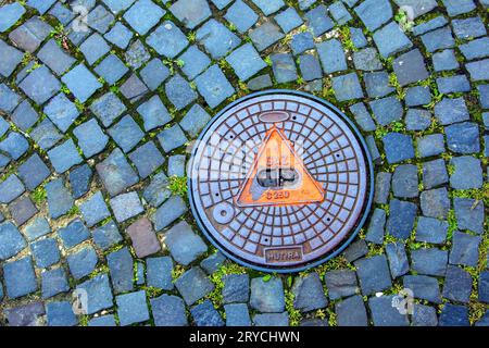 Manhole cover of the gas pipeline system. A massive metal hatch for access to city communications in the pavement. Stock Photo