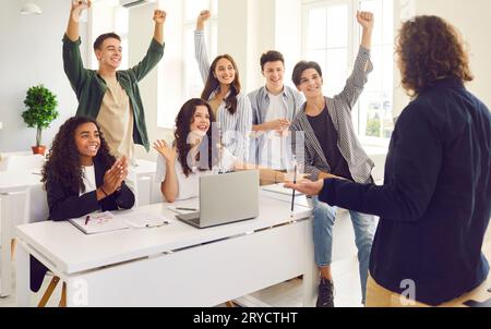 Cheerful multiracial students having fun celebrating success during teamwork in lecture. Stock Photo
