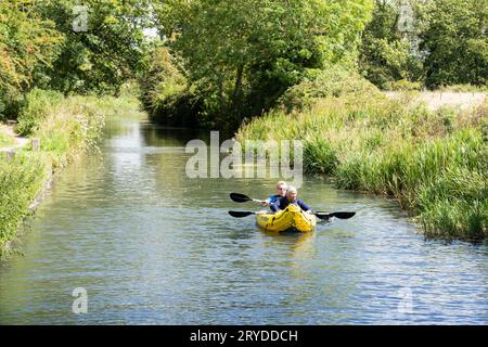 Things to do in Hampshire -  a man and woman kayaking in an inflatable boat on Basingstoke canal near Odiham on a summer's day. England Stock Photo