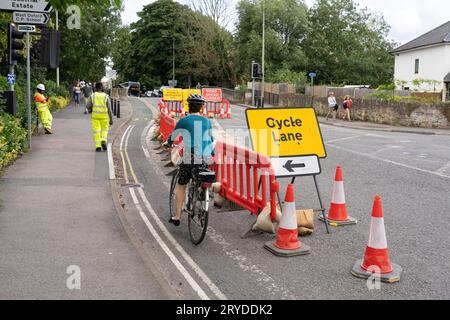 A woman cyclist wearing a helmet on the A420 Botley Road in Oxford, cycling down a temporary cycle lane due to roadworks. Summer 2023, England Stock Photo