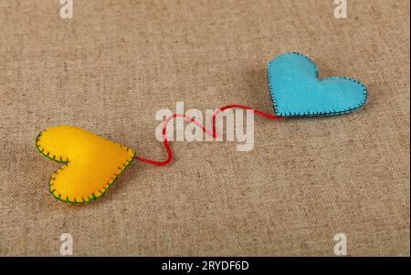 Two felt craft hearts, yellow and blue on canvas Stock Photo