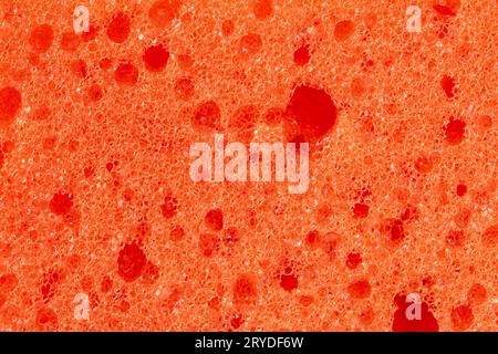 Abstract embossed orange background - the surface of a soft sanitary sponge. Orange foam sponge close-up Stock Photo