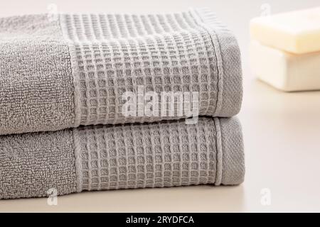 Bathroom accessories. Stack of gray soft towels and bar of soap on a gray background. Stock Photo