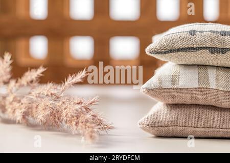 Domestic life. A stack of three pillows, a dry plant stem on a background of a wooden lattice. Stock Photo