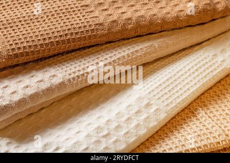 Stack of beige and cream colored waffle kitchen towels folded into folds close-up. Stock Photo
