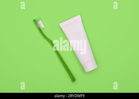 White toothpaste and plastic toothbrush on green Stock Photo