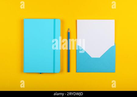 Blue notebook and paper envelope over yellow Stock Photo
