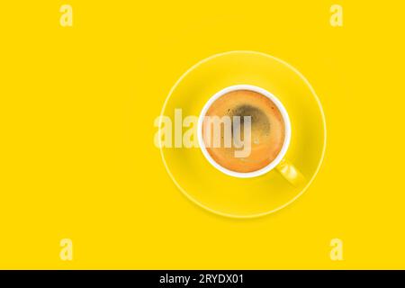 One full espresso coffee cup with saucer on yellow Stock Photo