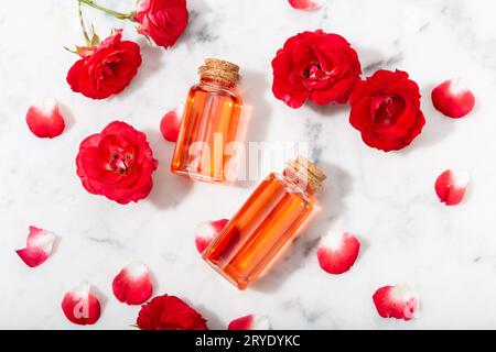 Perfumed Rose Water in glass bottle and small red roses with petals Stock Photo