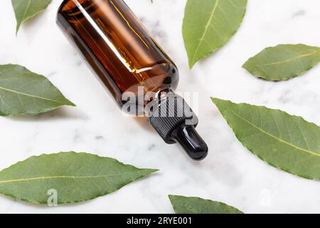 Herbal essential oil on marble table. Bay oil on glass bottle with dropper Stock Photo