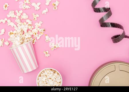 Popcorn bucket, film strip and film can on pink background Stock Photo