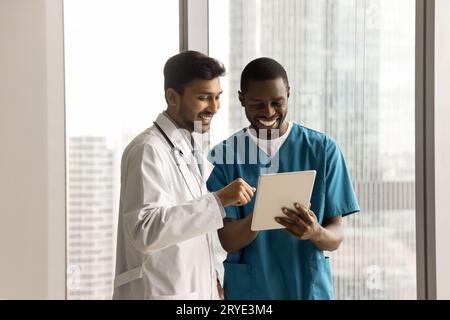 Two happy diverse doctors using tablet for healthcare discussion Stock Photo