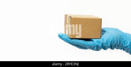Delivery man holding cardboard box in rubber gloves Stock Photo