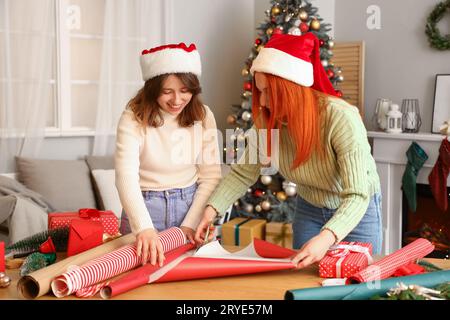 Young women cutting wrapping paper for Christmas gift at home Stock Photo