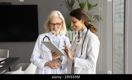 Two positive young and senior doctor women using tablet together Stock Photo