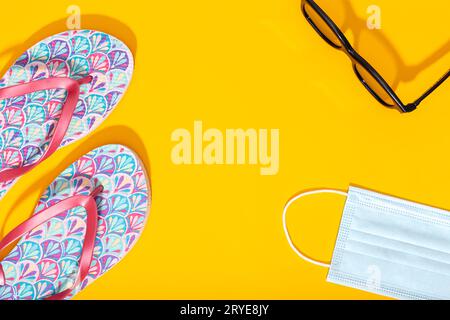 Flat lay composition with summer vacation accessories and face mask on yellow background Stock Photo