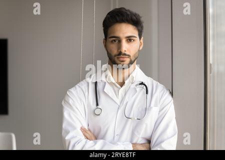 Serious handsome young Arab hospital physician man standing indoors Stock Photo