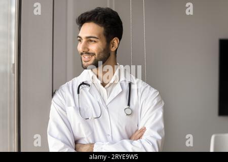 Positive successful Arab doctor man standing at window Stock Photo