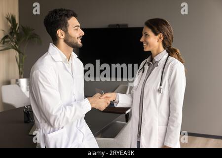 Two positive doctors shaking hands in clinic office Stock Photo