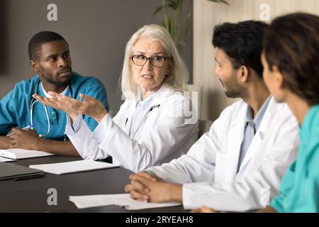 Serious senior head doctor talking to diverse hospital staff Stock Photo