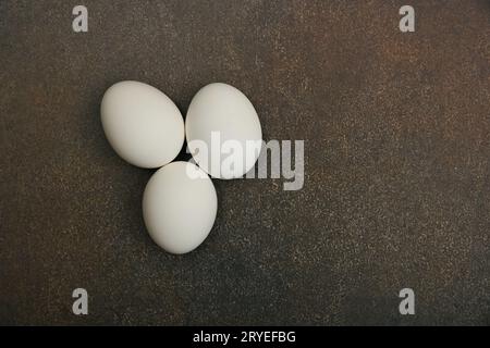Three white chicken eggs on dark table Stock Photo