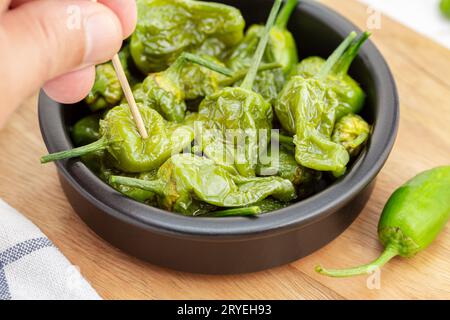 Hand picking a Cooked Padron peppers in a a bowl Stock Photo